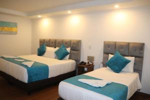 波哥大Hotel Bogota DC的一间卧室配有两张带蓝色枕头的床