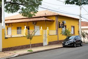 安娜兰迪亚Casarao Hostel - Analandia SP的一座黄色的房子,前面有一辆汽车