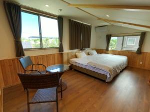 本部美丽海村旅馆的卧室配有一张床和一张桌子及椅子