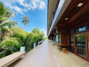 Damnoen Saduak丹农卡尔度假村的走廊上设有长椅和棕榈树的建筑