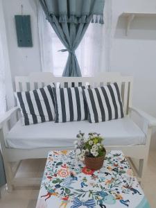 华欣普拉塔纳花园海滩度假酒店的白色的沙发,上面有一张桌子和一壶鲜花