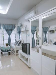 华欣普拉塔纳花园海滩度假酒店的白色客房,配有电视和床