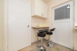 伦敦TDM Bachelot Lettings Ltd的厨房配有白色橱柜和2张凳子