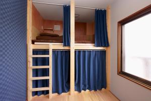 札幌Guesthouse OYADO SAPPORO的双层床配有蓝色窗帘和梯子