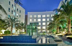 马斯喀特马斯喀特千年行政公寓酒店的 ⁇ 染酒店,拥有游泳池和棕榈树