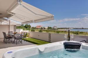普利拉卡Beachfront villas with hot tubs Sun Garden的庭院内的热水浴池,配有桌椅