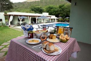 西波山Pousada Cantuá的餐桌上摆着早餐,桌边设有游泳池