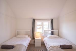 海滨韦尔斯港Avocet House的带窗户的客房内设有两张单人床。