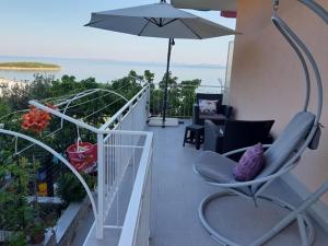普利莫顿Apartmani Vesna Miliša的一个带椅子和遮阳伞的阳台,并享有海景。