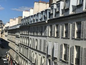 巴黎Le Basile Hôtel的街道上设有白色百叶窗的建筑