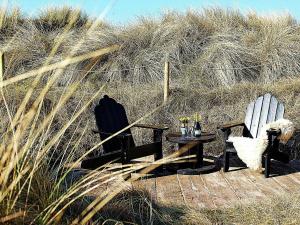 维泽桑讷6 person holiday home in Hvide Sande的两把椅子和一张桌子,在一些高大的草地前面