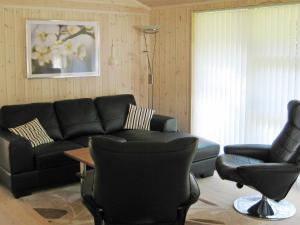 Engesvang6 person holiday home in Silkeborg的客厅配有黑色沙发和两把椅子
