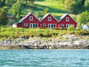SørbøFour-Bedroom Holiday home in Sørbøvåg 1的水边山丘上的红房子