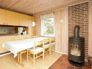 亨讷斯特兰德5 person holiday home in Henne的厨房配有桌子和燃木炉。