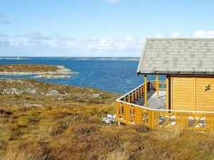 TuvnesThree-Bedroom Holiday home in Dyrvik的海边小山上的木屋