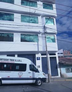 瓦拉斯Artesonraju Hostel Huaraz的停在大楼前的白色货车