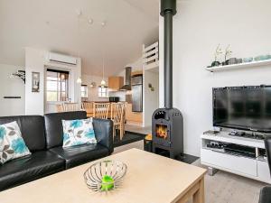 维泽桑讷6 person holiday home in Hvide Sande的客厅配有黑色真皮沙发和燃木炉。