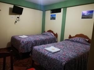 瓦拉斯Artesonraju Hostel Huaraz的客房设有两张床和一台墙上的电视。