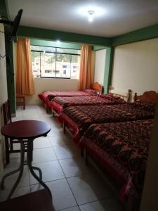瓦拉斯Artesonraju Hostel Huaraz的一间卧室设有两张床、一张桌子和一个窗口