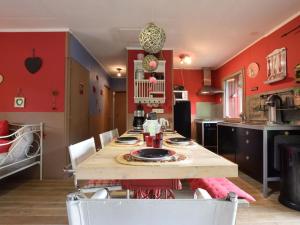 胡法利兹Chalet in a green and peaceful environment的厨房设有红色的墙壁和一张木桌及椅子