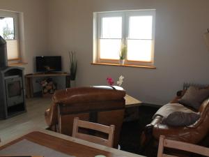 克勒珀林Comfy Farmhouse in Brusow with Garden的客厅配有皮革家具和2扇窗户。