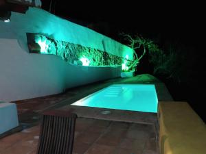 阿尔考辛Belvilla by OYO La Zamarra的夜间游泳池,墙上有灯