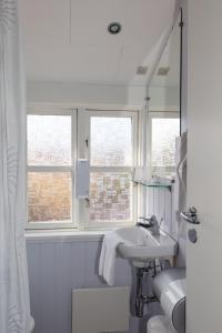 斯卡恩Foldens Hotel Annex的白色浴室设有水槽和2扇窗户