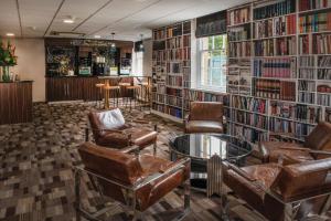 温莎海利校长会议博蒙特庄园酒店的图书馆配有皮椅、桌子和书籍