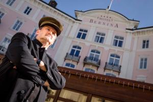 萨梅丹Kleos Hotel Bernina 1865的站在建筑物前身戴帽子的人