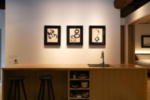 萩市Hagi Kannuki 168 -萩 閂いろは-的厨房墙上有三幅画,还有三把凳子