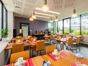 布洛涅-比扬古Lagrange Apart’Hotel Paris-Boulogne的餐厅设有木桌、椅子和窗户。