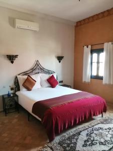 瓦尔扎扎特布舍多摩洛哥传统庭院住宅的一间卧室配有一张带红色毯子的大床