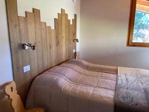 BedolloEco Chalet Nonno Silvano的一间卧室配有一张带木制床头板的床