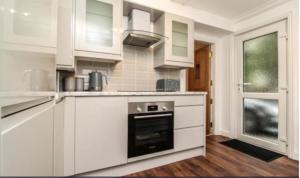 布伦特伍德Charming Victoria Conversion Flat in Brentwood with a Garden & Free Parking的厨房配有白色橱柜和烤箱。