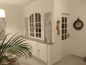 费拉古多Three Palms Apartment的厨房配有白色橱柜和墙上的时钟