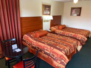 尤宁城Country Hearth Inn-Union City的酒店客房带两张床和一张桌子以及椅子。