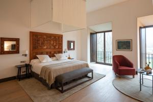 莱昂Parador de Turismo de León的一间卧室配有一张床和一张红色椅子