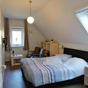 温特斯韦克Veenemaat的卧室配有床、椅子和窗户。