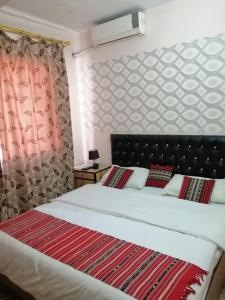 安曼哈穆达酒店的一间卧室配有一张带红色毯子的大床
