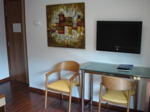 格拉诺列尔斯鸢尾花酒店的一间配备有桌子和两把椅子及一台电视的房间