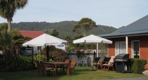 格雷默斯艾派恩玫瑰汽车旅馆的一个带桌子和遮阳伞及烧烤设施的庭院。