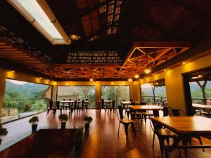 蒙纳The Wild Trails Munnar Resort的餐厅设有桌椅和大窗户。