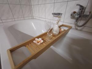 罗伊特Ferienwohnung Ela的浴缸,带葡萄酒玻璃和鲜花的木制托盘