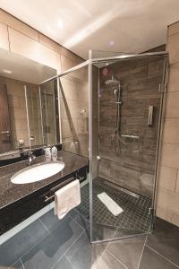 诺德施泰特PLAZA Premium Parkhotel Norderstedt的一间带玻璃淋浴和水槽的浴室