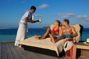 Komandoo卡曼都岛Spa度假酒店的一群人坐在海滩上的床上