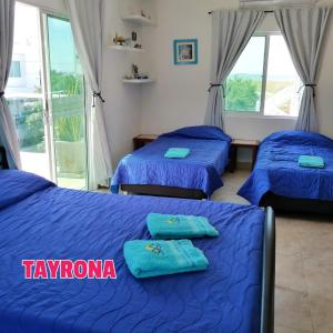 圣玛尔塔Casa de Mony的配有蓝色床单的客房内的三张床