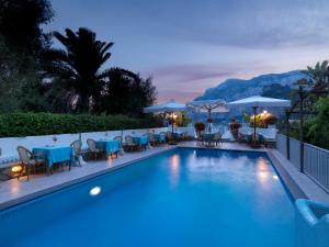 卡普里布鲁奈拉别墅酒店的一个带桌椅和遮阳伞的游泳池