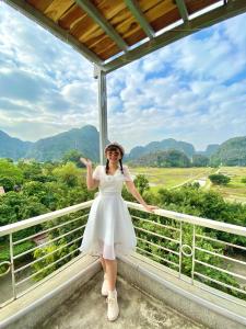 宁平Hang Mua Central Homestay的站在一个有山背景的阳台上的女人