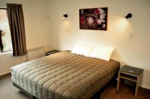 皇后镇圣詹姆斯公寓式酒店的卧室配有一张床,墙上挂着一幅画
