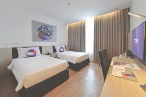 北干巴鲁FOX Hotel Pekanbaru的酒店客房设有两张床和一台平面电视。